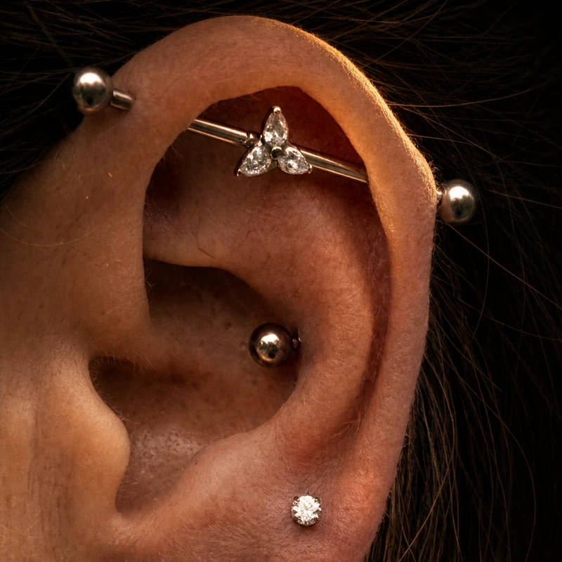 Piercing industrial y helix con circonitas en oreja, ejemplo de joyería de titanio en La Mamba Negra, estudio de piercing en Gijón